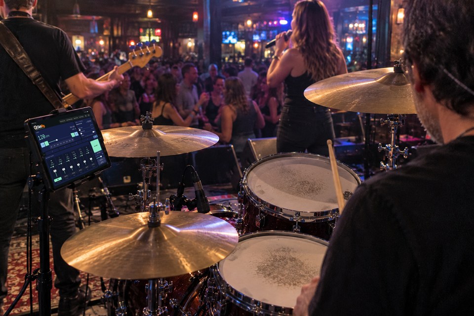 Drummer performing with a band in a club, with ClickRig on a nearby iPad.